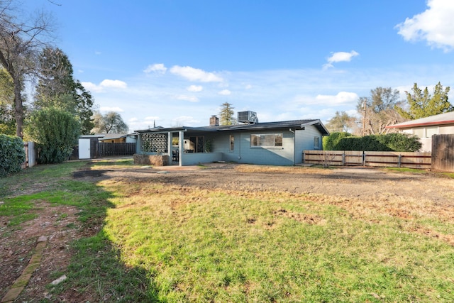 back of house with a storage shed, a yard, and central air condition unit