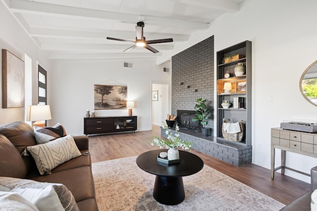 living room with beamed ceiling, ceiling fan, a fireplace, and hardwood / wood-style floors