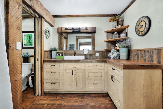 kitchen with wood walls, sink, dark hardwood / wood-style flooring, ornamental molding, and cream cabinetry