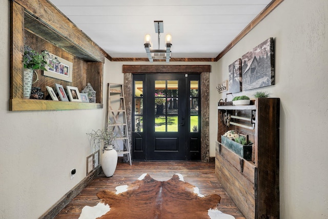 entrance foyer with ornamental molding, dark wood-type flooring, and a chandelier