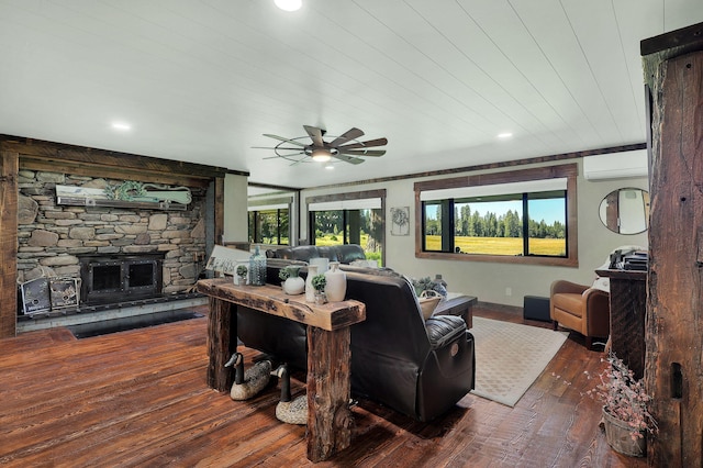 living room featuring dark wood-type flooring, wood ceiling, a wall unit AC, ceiling fan, and a fireplace