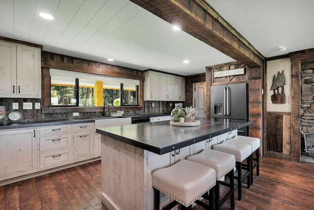 kitchen with a kitchen island, sink, high end refrigerator, a kitchen breakfast bar, and dark wood-type flooring