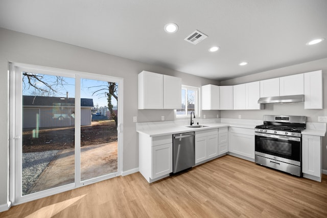 kitchen featuring stainless steel appliances, sink, white cabinets, and light wood-type flooring