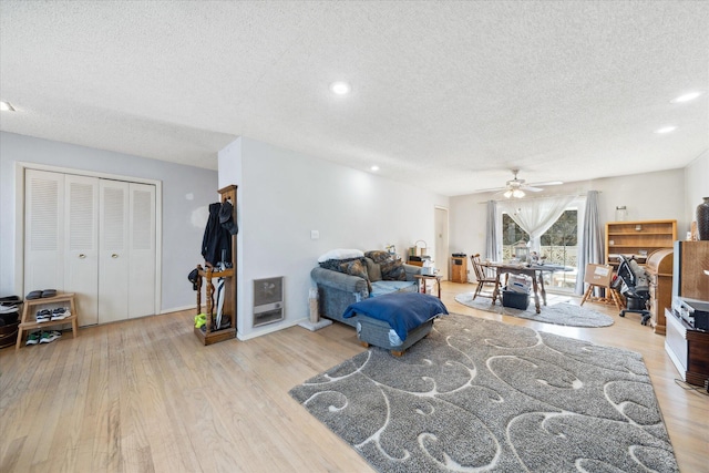 living room featuring ceiling fan, light hardwood / wood-style floors, and a textured ceiling