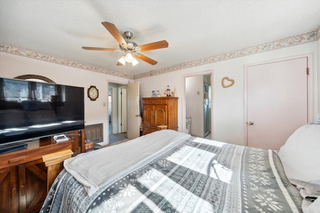 bedroom featuring ceiling fan, ensuite bathroom, and a textured ceiling