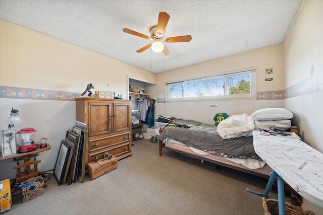 carpeted bedroom with ceiling fan and a textured ceiling