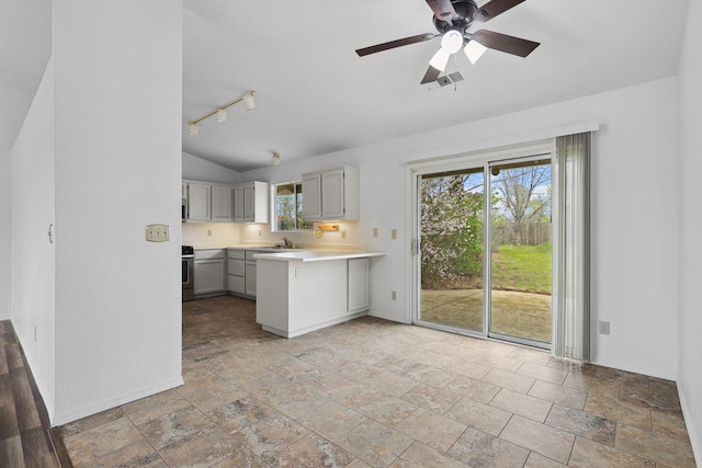 kitchen with lofted ceiling, ceiling fan, a peninsula, light countertops, and a sink