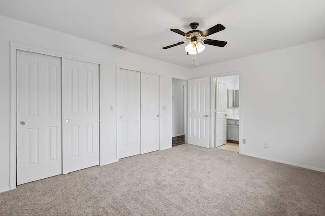 unfurnished bedroom featuring baseboards, visible vents, connected bathroom, carpet floors, and two closets