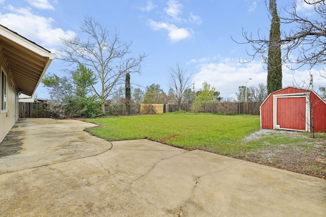 view of yard featuring a storage shed, a patio area, a fenced backyard, and an outbuilding