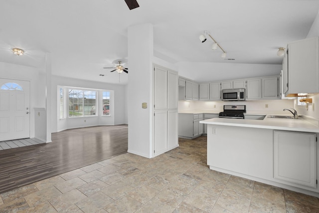 kitchen with light countertops, appliances with stainless steel finishes, open floor plan, vaulted ceiling, and a peninsula