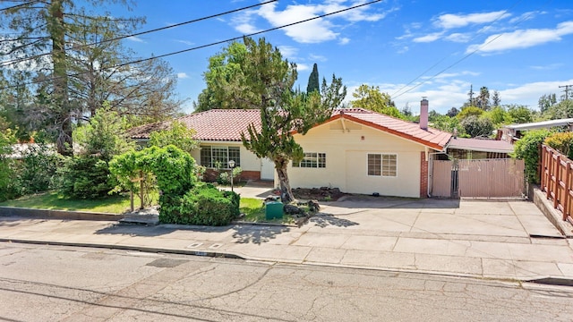 view of front of property featuring fence, a tile roof, a gate, and brick siding