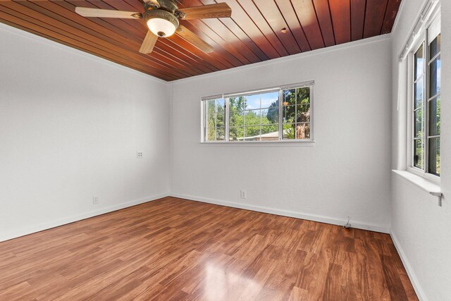 empty room featuring wood ceiling, baseboards, wood finished floors, and ceiling fan