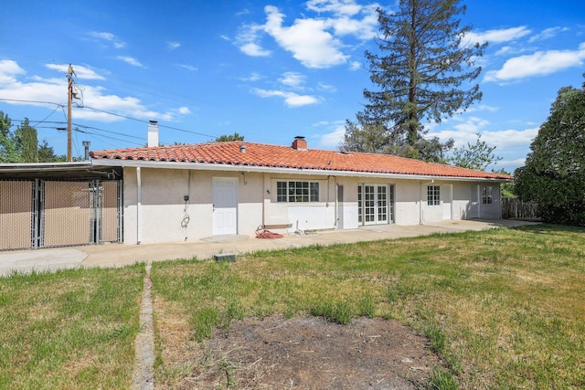 rear view of house with a tile roof, a patio area, a chimney, a lawn, and stucco siding