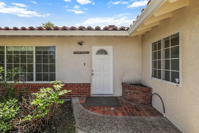 doorway to property with a tile roof and stucco siding