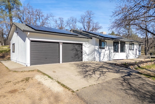 ranch-style house with a garage and solar panels