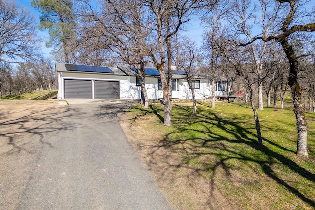 view of front facade featuring a garage, a front lawn, and solar panels