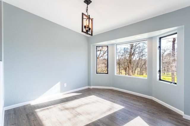 empty room with an inviting chandelier and dark hardwood / wood-style floors