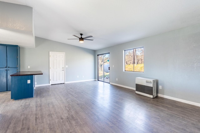 unfurnished living room with dark wood-type flooring, ceiling fan, lofted ceiling, and heating unit