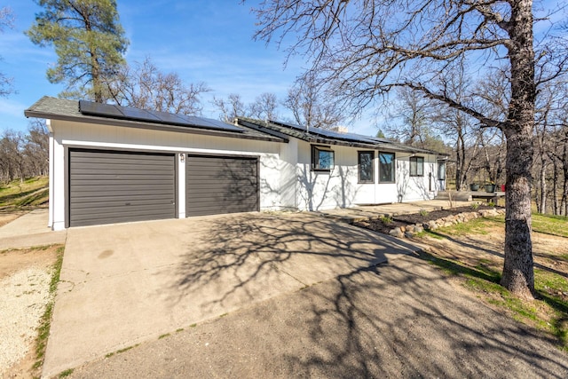 single story home with a garage and solar panels