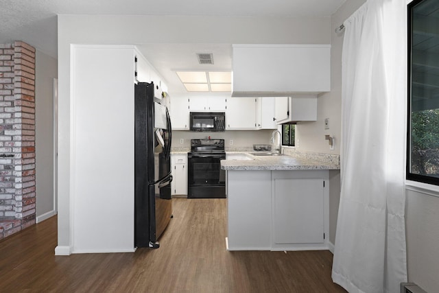 kitchen with dark wood-type flooring, sink, black appliances, kitchen peninsula, and white cabinets