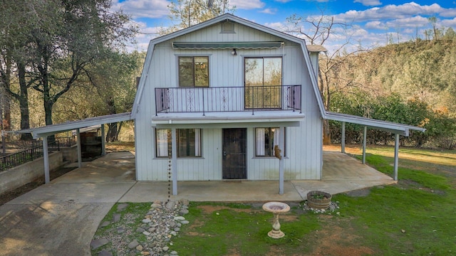 rear view of property featuring a carport, a balcony, and a lawn