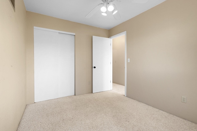 unfurnished bedroom with ceiling fan, light colored carpet, and a closet