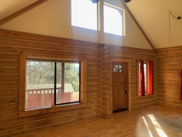 interior space featuring beam ceiling, hardwood / wood-style floors, log walls, and high vaulted ceiling