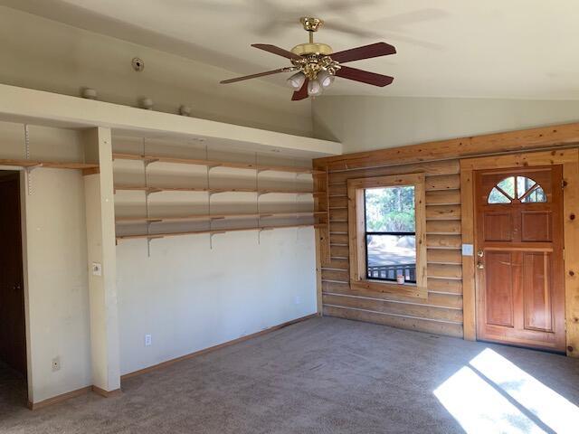 carpeted entrance foyer featuring vaulted ceiling and ceiling fan