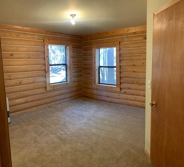 carpeted empty room featuring a healthy amount of sunlight and log walls