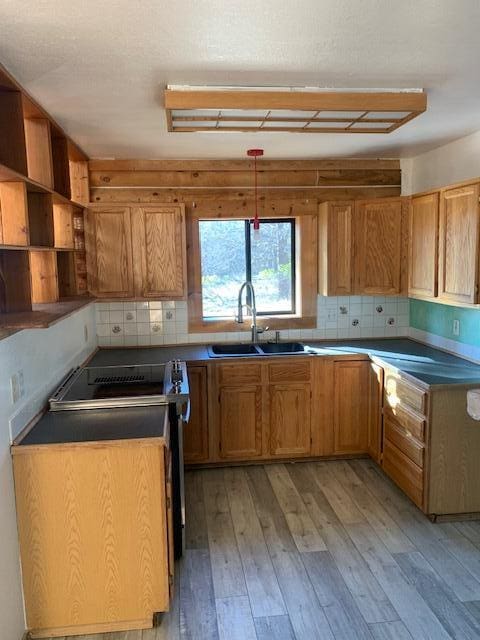 kitchen with sink, light hardwood / wood-style flooring, hanging light fixtures, electric range, and decorative backsplash