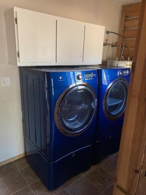 washroom with cabinets, dark tile patterned flooring, and washing machine and dryer