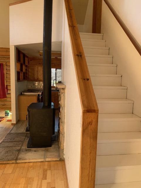 stairs featuring wood-type flooring and a wood stove