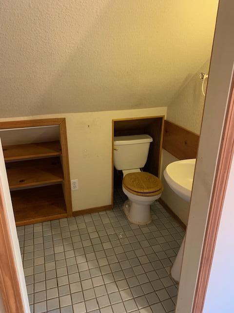 bathroom featuring tile patterned flooring, vaulted ceiling, and toilet