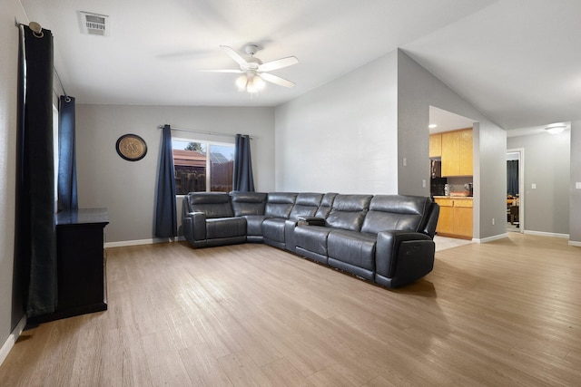 living room with light hardwood / wood-style flooring, vaulted ceiling, and ceiling fan