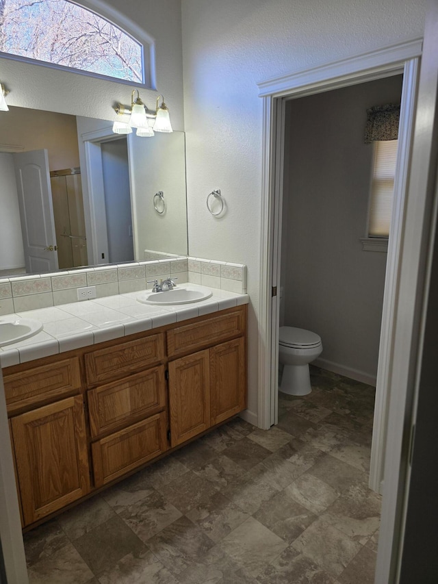 bathroom featuring vanity, walk in shower, and toilet