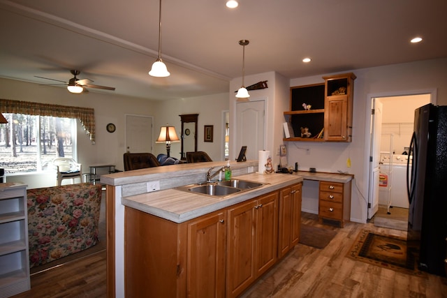 kitchen featuring black fridge, dark hardwood / wood-style floors, a kitchen island with sink, and sink