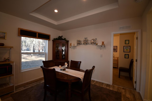 dining space featuring dark hardwood / wood-style floors and a raised ceiling