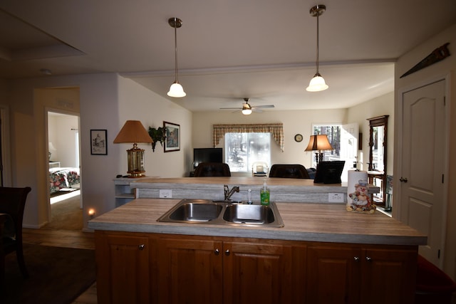 kitchen with ceiling fan, decorative light fixtures, sink, and a center island with sink