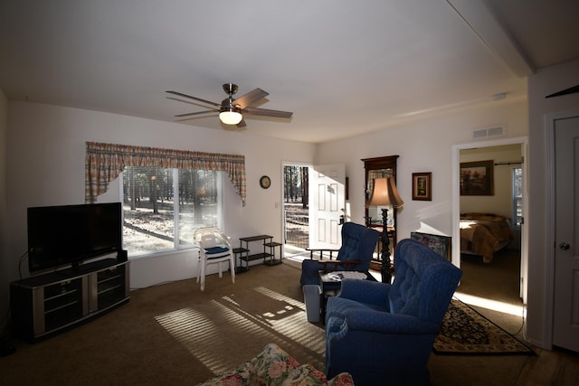 living room featuring ceiling fan and dark carpet