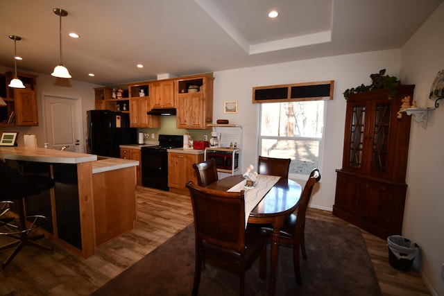 dining area with hardwood / wood-style flooring and a raised ceiling