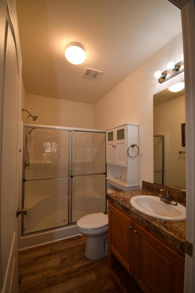 bathroom with vanity, toilet, hardwood / wood-style floors, and walk in shower