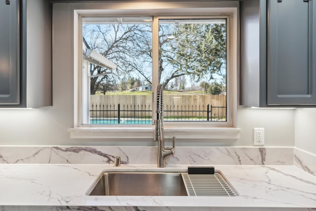 kitchen featuring gray cabinets, sink, and light stone counters