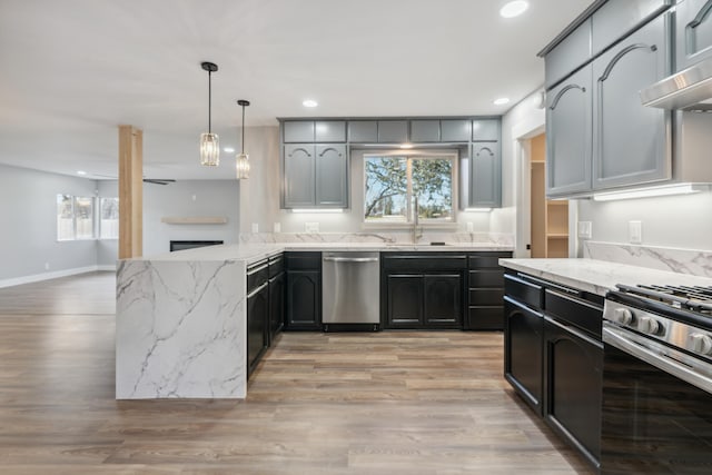 kitchen with extractor fan, light hardwood / wood-style flooring, kitchen peninsula, pendant lighting, and stainless steel appliances