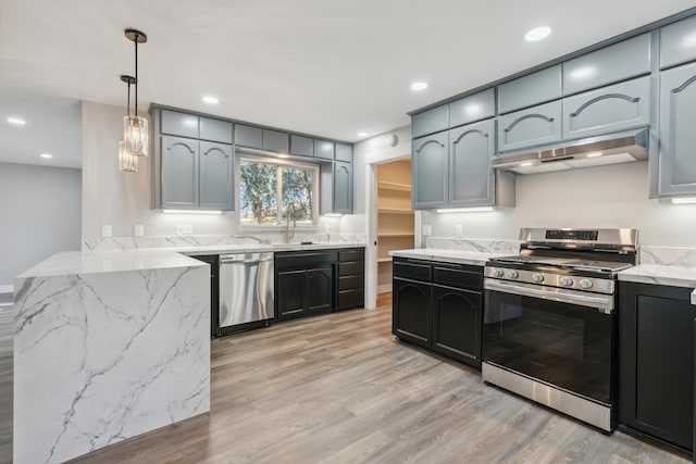 kitchen with sink, hanging light fixtures, stainless steel appliances, light hardwood / wood-style floors, and light stone countertops