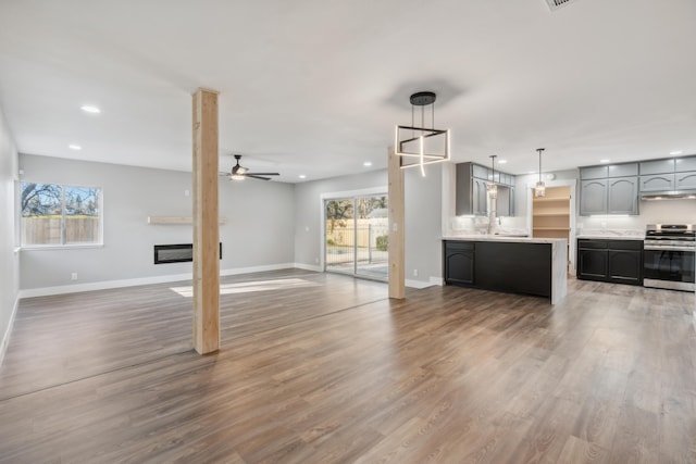 unfurnished living room with hardwood / wood-style flooring, ceiling fan, and sink