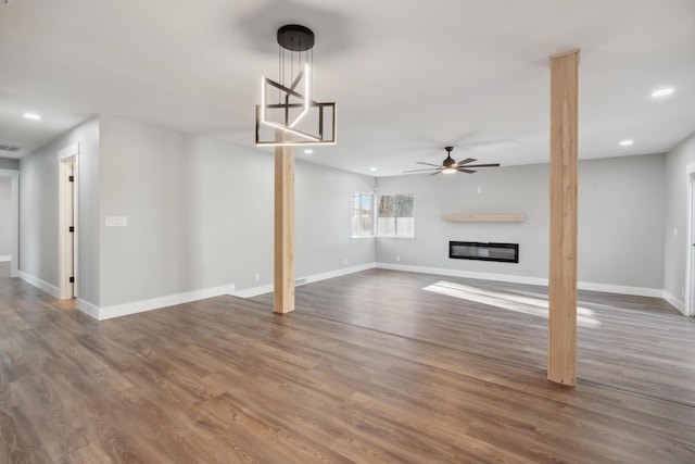 unfurnished living room featuring ceiling fan and dark hardwood / wood-style flooring