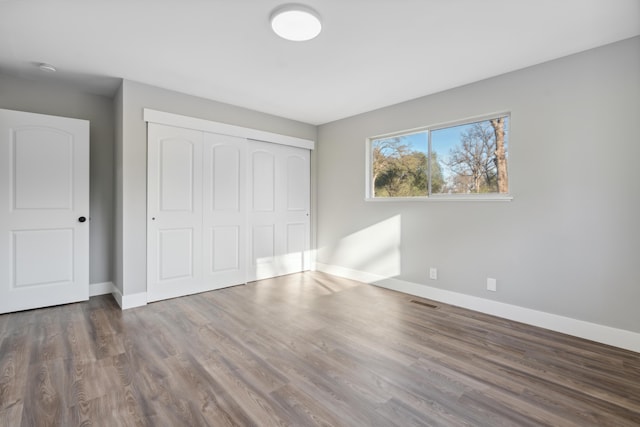 unfurnished bedroom featuring dark hardwood / wood-style floors and a closet