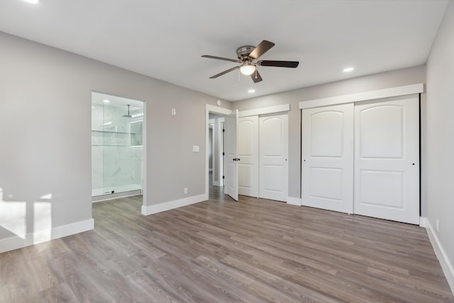 unfurnished bedroom with multiple closets, ceiling fan, hardwood / wood-style floors, and ensuite bath