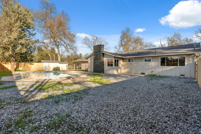 rear view of property with a fenced in pool and a patio