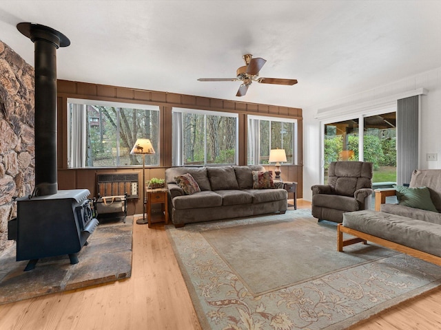 living room featuring hardwood / wood-style flooring, ceiling fan, and a wood stove